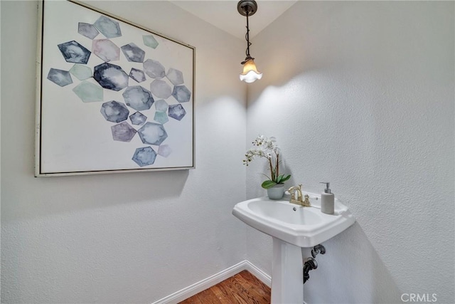 bathroom with a sink, baseboards, and wood finished floors