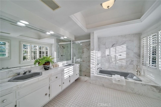 full bathroom with a tray ceiling, double vanity, a marble finish shower, and a sink