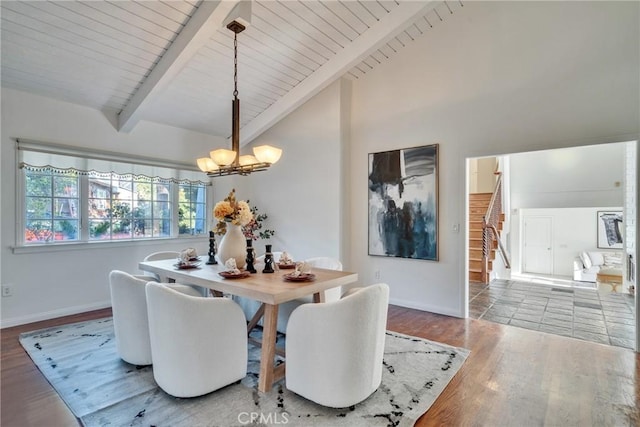 dining space with a notable chandelier, lofted ceiling with beams, wood finished floors, stairway, and baseboards