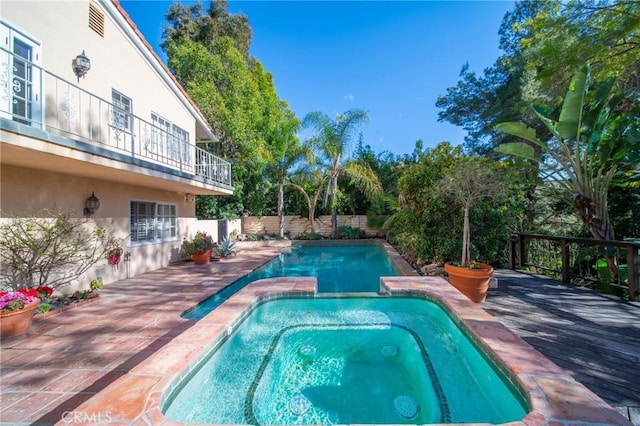 view of pool with a patio area, a pool with connected hot tub, and fence