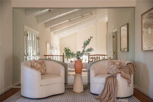 living area with vaulted ceiling with beams and baseboards