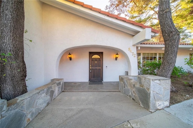 entrance to property with stucco siding and a tile roof