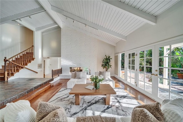 living area with stairway, wood finished floors, high vaulted ceiling, track lighting, and beamed ceiling