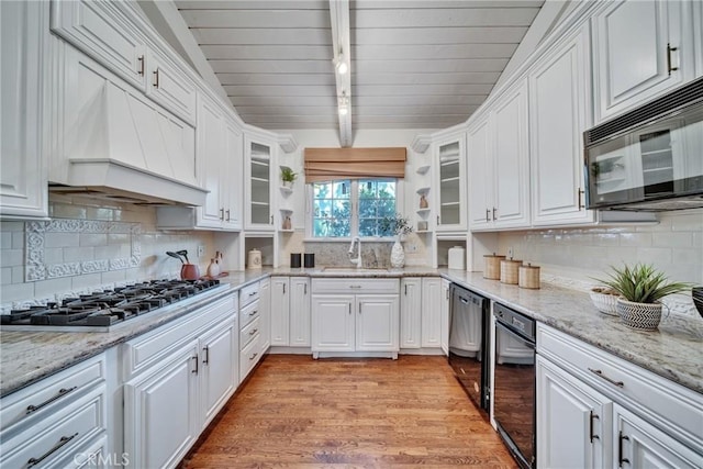 kitchen featuring beamed ceiling, a sink, white cabinetry, stainless steel gas stovetop, and black microwave