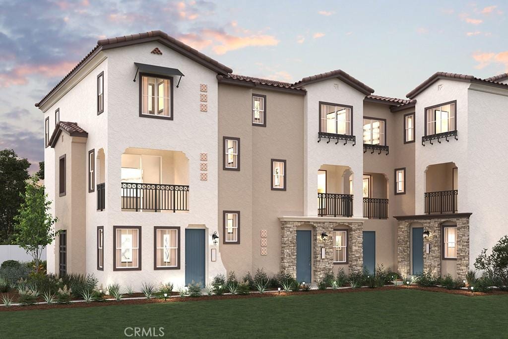 mediterranean / spanish home with stucco siding, a yard, and a tiled roof