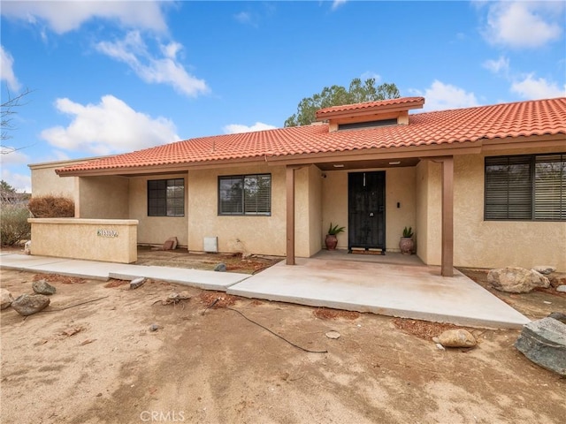 rear view of property with stucco siding and a tile roof