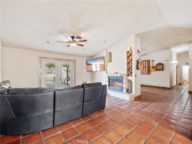 tiled living room featuring a lit fireplace, ceiling fan, vaulted ceiling, french doors, and a textured ceiling