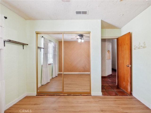 interior space with visible vents, baseboards, a ceiling fan, and wood finished floors