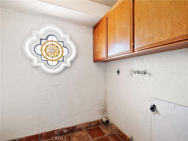 washroom featuring electric dryer hookup, cabinet space, baseboards, hookup for a washing machine, and a textured wall