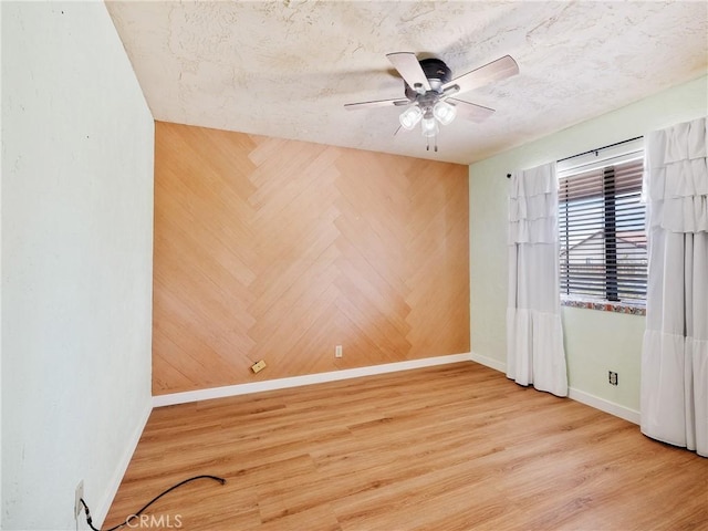 spare room with a textured ceiling, baseboards, ceiling fan, and wood finished floors