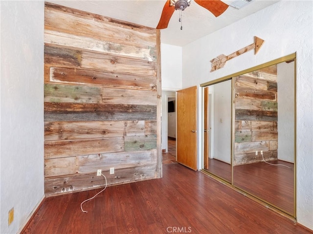 spare room featuring wood finished floors, wooden walls, and a ceiling fan