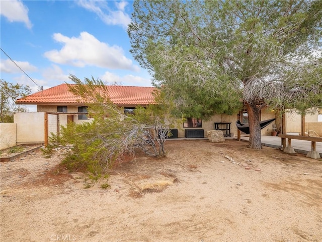 view of front of property with stucco siding, fence, and a tile roof