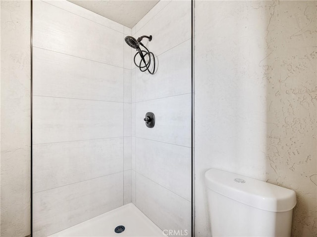 bathroom featuring a tile shower and toilet