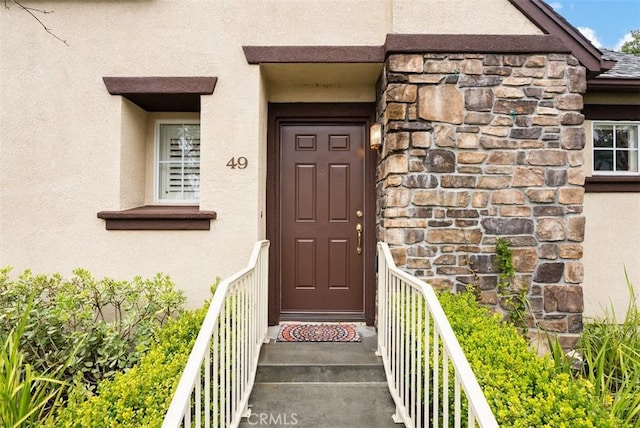 property entrance featuring stucco siding and stone siding