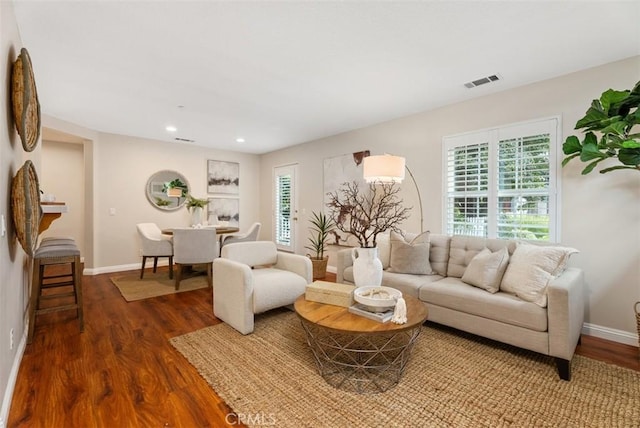 living room with recessed lighting, visible vents, baseboards, and wood finished floors