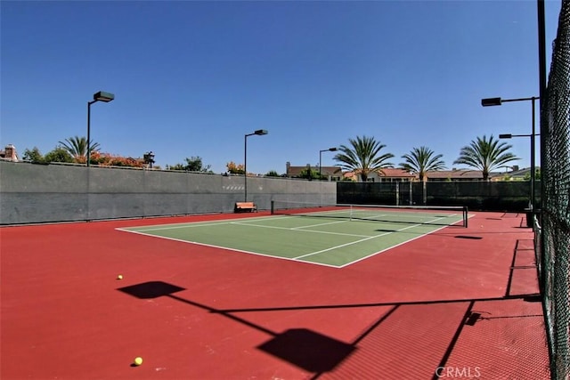 view of tennis court with community basketball court and fence