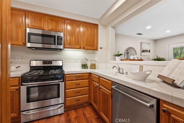 kitchen featuring visible vents, brown cabinets, appliances with stainless steel finishes, and a sink