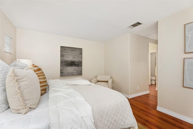 bedroom with visible vents, baseboards, and wood finished floors