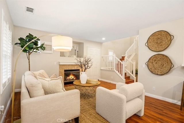 living area with visible vents, stairway, wood finished floors, and baseboards