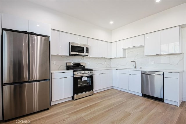 kitchen with a sink, white cabinetry, appliances with stainless steel finishes, and light countertops