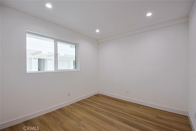 unfurnished room with recessed lighting, wood finished floors, and baseboards