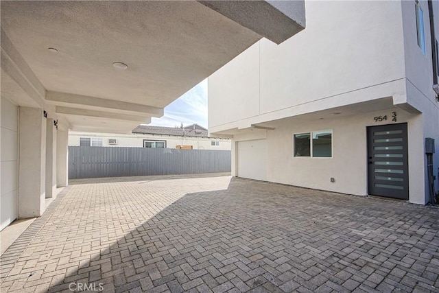 view of patio / terrace with decorative driveway, a garage, and fence