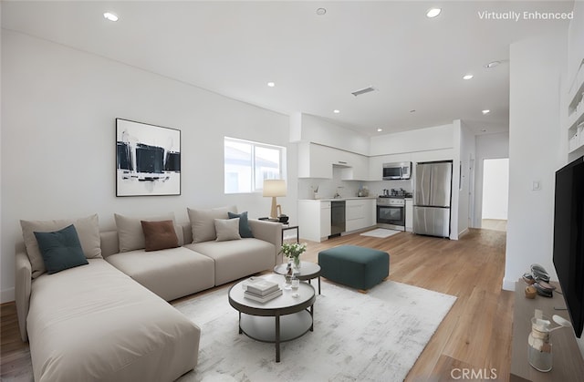 living area with light wood finished floors, visible vents, and recessed lighting