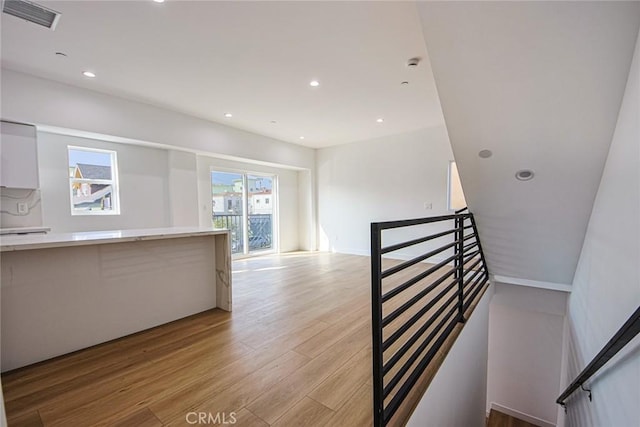 stairway featuring recessed lighting, wood finished floors, and visible vents