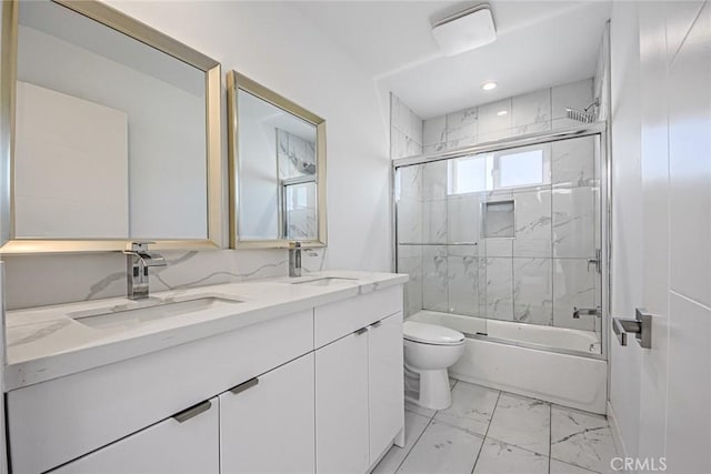 bathroom with toilet, marble finish floor, bath / shower combo with glass door, and a sink