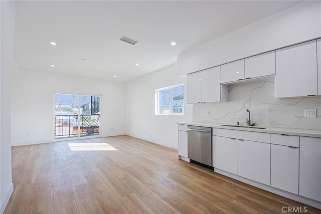 kitchen featuring visible vents, white cabinetry, a sink, stainless steel dishwasher, and light wood-type flooring