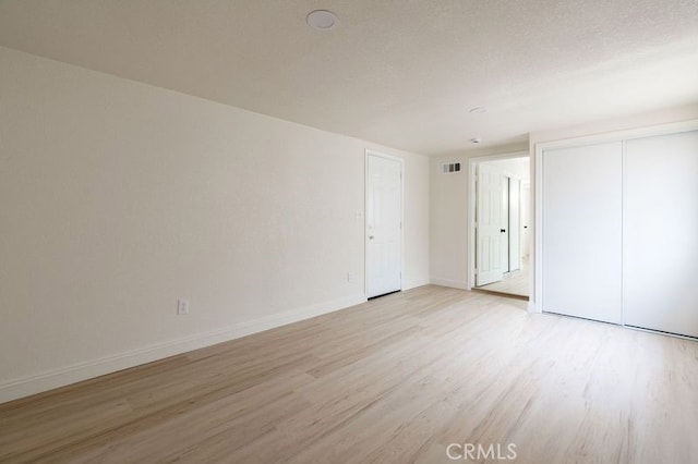 unfurnished bedroom featuring light wood-type flooring, visible vents, baseboards, and a textured ceiling