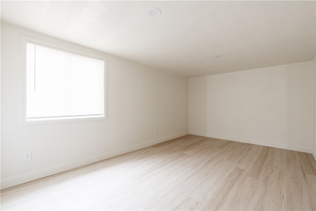 unfurnished room with light wood-type flooring and baseboards