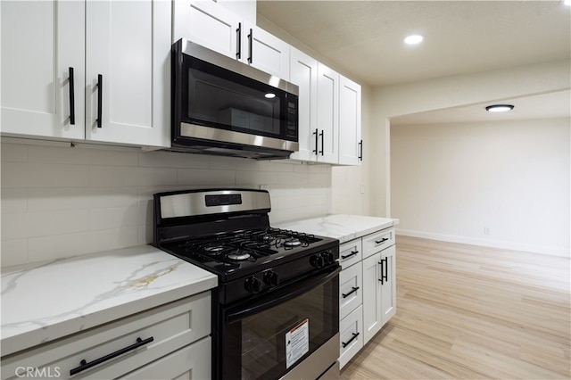 kitchen featuring gas stove, stainless steel microwave, white cabinets, and light wood finished floors