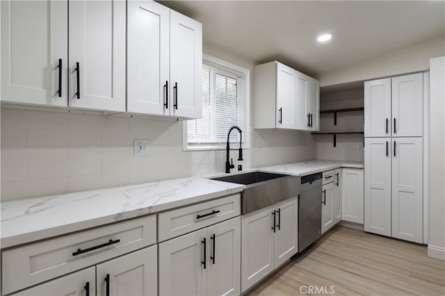 kitchen with a sink, open shelves, stainless steel dishwasher, white cabinetry, and light wood finished floors