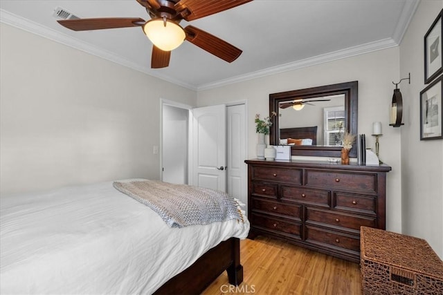 bedroom featuring visible vents, ornamental molding, a ceiling fan, a closet, and light wood-style floors