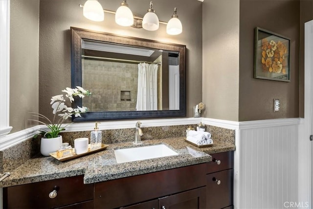 full bathroom with a shower with curtain, wainscoting, and vanity