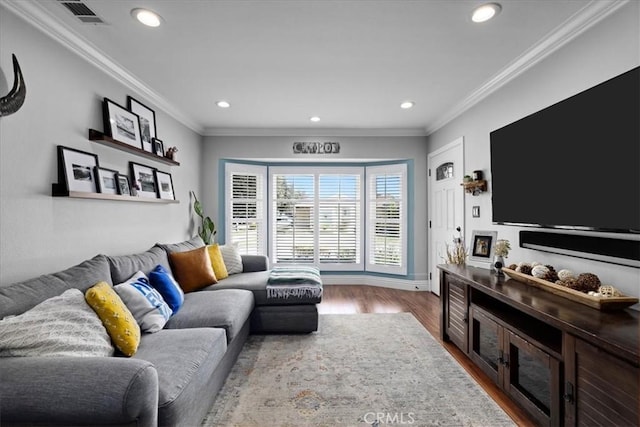 living area featuring wood finished floors, baseboards, visible vents, recessed lighting, and ornamental molding