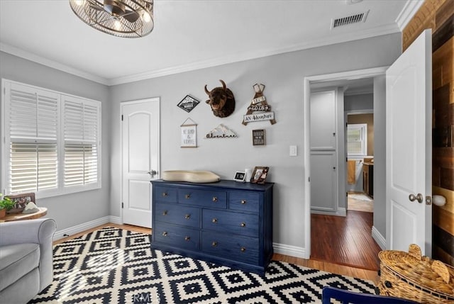 living area with crown molding, wood finished floors, visible vents, and baseboards