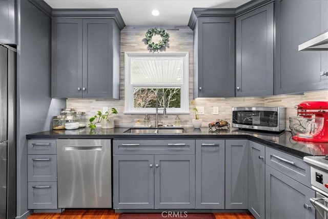 kitchen with decorative backsplash, appliances with stainless steel finishes, gray cabinetry, and a sink