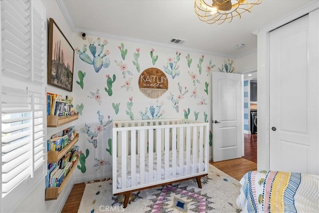 bedroom with visible vents, wallpapered walls, wood finished floors, and ornamental molding