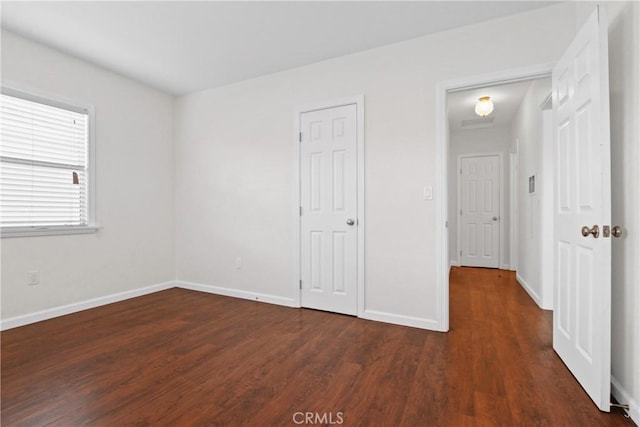 unfurnished bedroom featuring dark wood-type flooring and baseboards