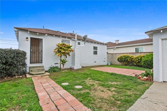 back of house with a patio, a yard, fence, and stucco siding