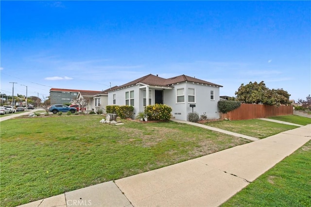 view of front of home with stucco siding, a front lawn, and fence