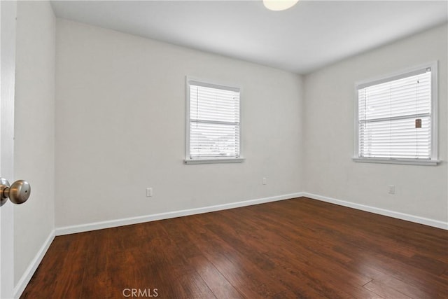 spare room with a wealth of natural light, baseboards, and hardwood / wood-style floors