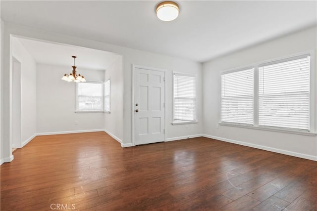 entrance foyer featuring baseboards, an inviting chandelier, and hardwood / wood-style flooring