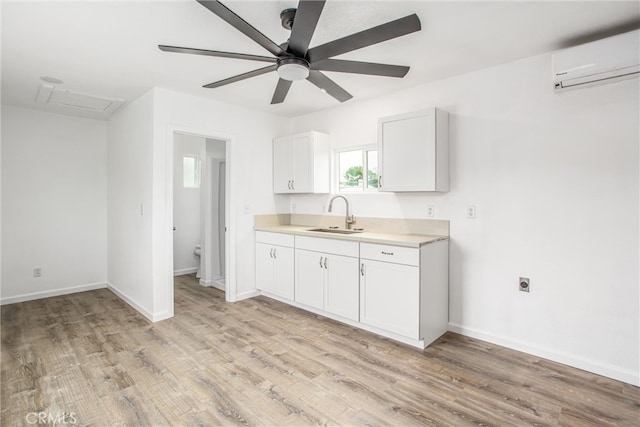 kitchen with a sink, light wood-style flooring, light countertops, and a wall mounted AC