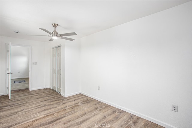 unfurnished bedroom featuring a closet, a ceiling fan, baseboards, and wood finished floors