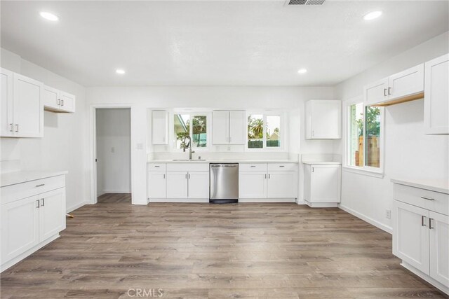 kitchen with stainless steel dishwasher, white cabinets, and light wood-type flooring