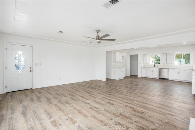 unfurnished living room featuring visible vents, baseboards, ceiling fan, light wood-style floors, and a sink