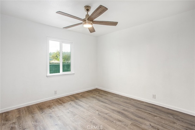 spare room featuring ceiling fan, baseboards, and wood finished floors